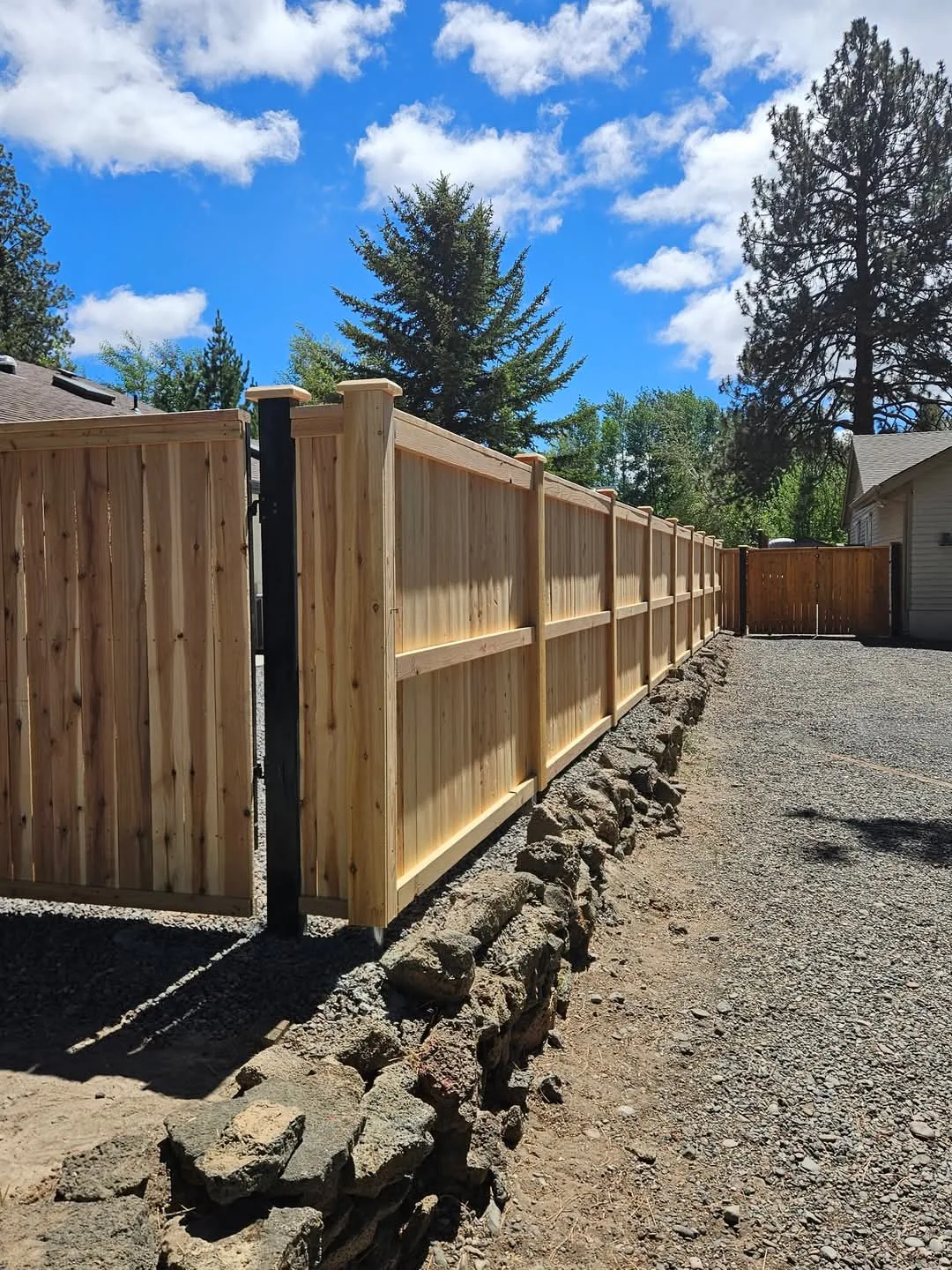 Natural wood fence extending beside a gravel pathway